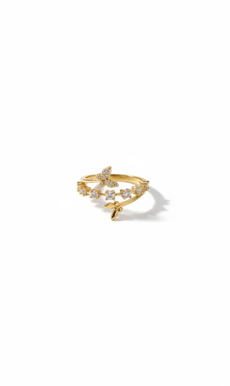 A delicate gold ring featuring a small bow at the center, adorned with tiny clear stones along the band, set against a plain white background with a soft shadow.
Grishita Jewellery