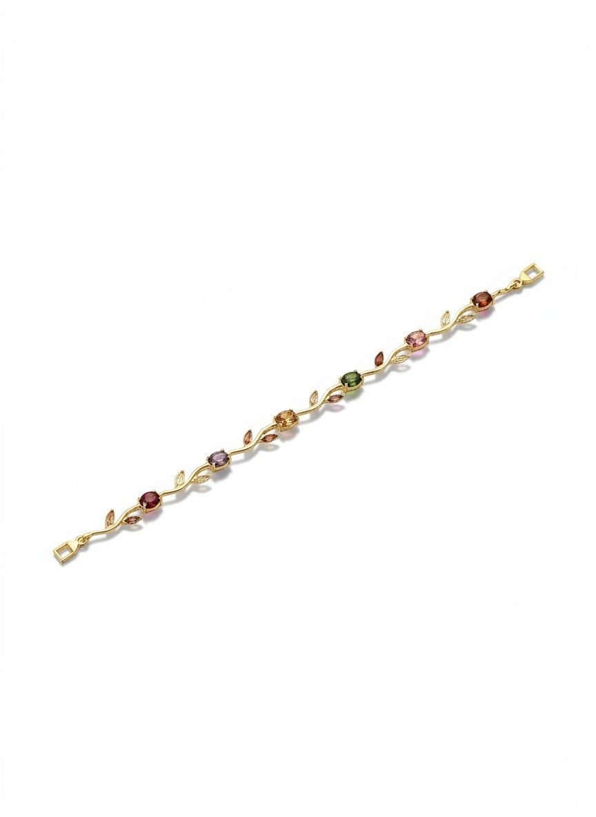 A delicate gold bracelet featuring a vine and leaf motif with small, colorful gemstone accents in red, pink, green, and purple, displayed on a clean white background.
Grishita Jewellery