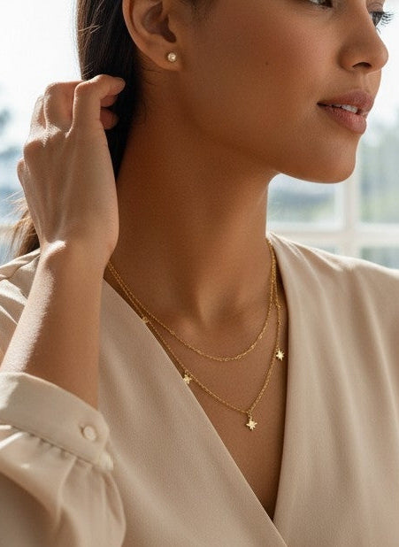 A woman in a cream satin blouse is shown in a bright home office setting, with a text overlay reading '316L Stainless Steel. Anti-Tarnish, Affordable Luxury'.