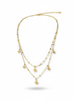 A gold multi-layer necklace featuring delicate chain strands and small starburst charms, displayed against a clean white background.